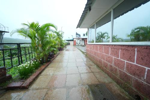 a walkway outside of a house with palm trees at Shivay Resort in Mahabaleshwar