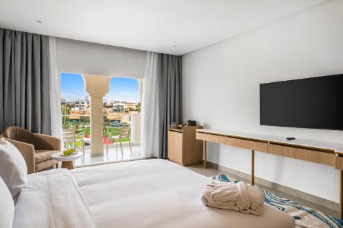 a hotel room with a bed and a flat screen tv at Pickalbatros Palais Des Roses - Agadir - All Inclusive in Agadir