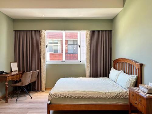 a bedroom with a bed and a desk and a window at 寶格儷舍 in Tainan