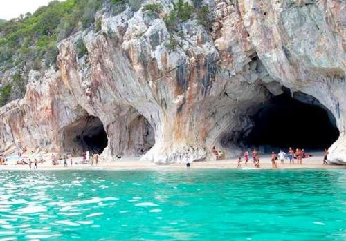 a group of people on a beach in front of a cave at B&B Luce Viola in Dorgali
