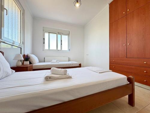 a white bedroom with two beds and a window at El Greco Apartment, in nature, with private yard - No 7 in Zipárion