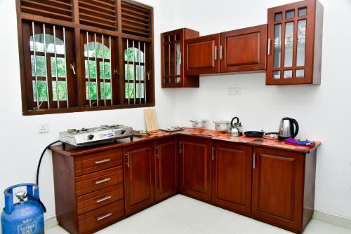 a kitchen with wooden cabinets and a stove at Osha Villa in Aluthgama