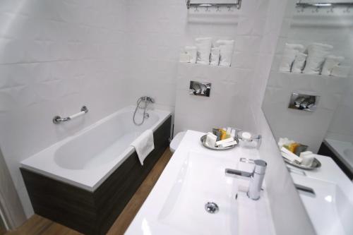 Un baño blanco con bañera y lavabo. en White Tower Mamaia VA Studio, en Mamaia