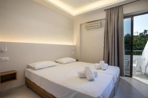 a bedroom with two beds with white sheets and a window at Nikos BnB in Faliraki