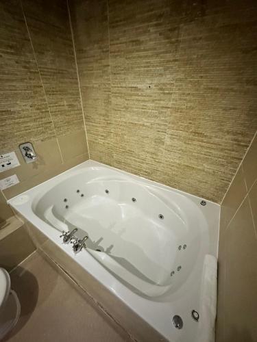 a white tub in a bathroom with a tiled wall at White Star Line Hotel in Liverpool