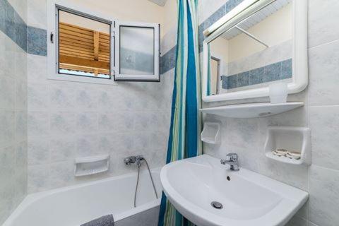 a bathroom with a sink and a mirror and a tub at Villa Georgia in Argassi