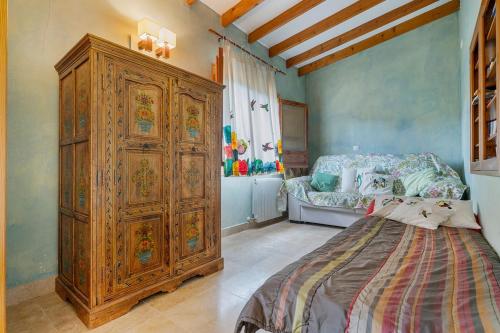 a bedroom with a large wooden cabinet next to a bed at Villa Rancallosa con barbacoa, wifi y piscina privada in Relleu
