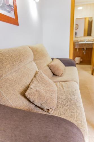 a couch with pillows on it in a living room at Apartamentos Turisticos Las Yucas in Torre del Mar