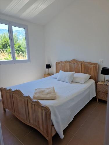 - une chambre avec un grand lit en bois et 2 fenêtres dans l'établissement Casa Figarella, à Calenzana