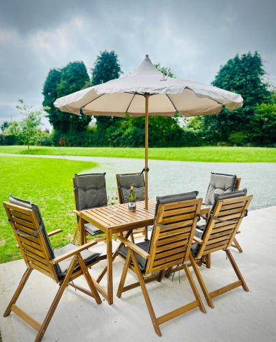 a wooden table with four chairs and an umbrella at Cobblers Walk - Luxury Country Getaway 