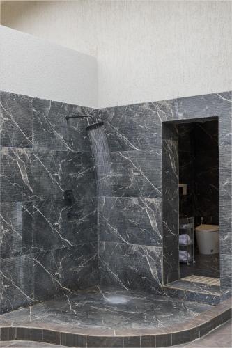 a bathroom with a shower in a black marble wall at Sitara Palace and Resort in Bhopal