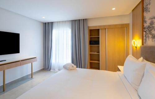a bedroom with a large white bed and a television at Pickalbatros Palais Des Roses - Agadir - All Inclusive in Agadir