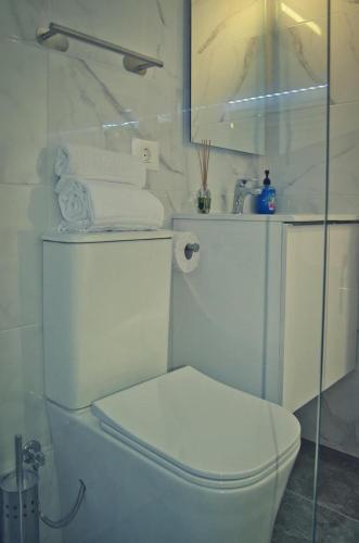 a white bathroom with a toilet and towels at La Ladera in Frontera