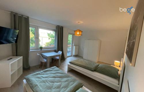 a bedroom with a bed and a desk and a tv at BEGE APARTMENTS WorkVibe Stay in Duisburg