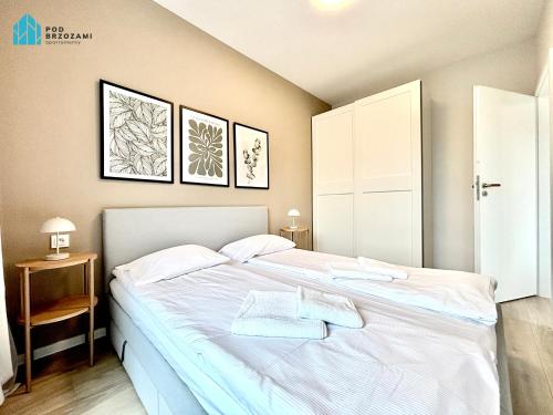 a bedroom with a bed with two towels on it at Pod Brzozami Apartamenty Let's Sea Gąski in Gąski