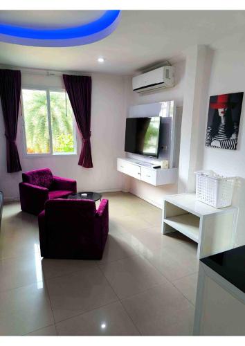 a living room with purple furniture and a flat screen tv at Titanic Residence-7 minute walk to the Beach in Pattaya Central
