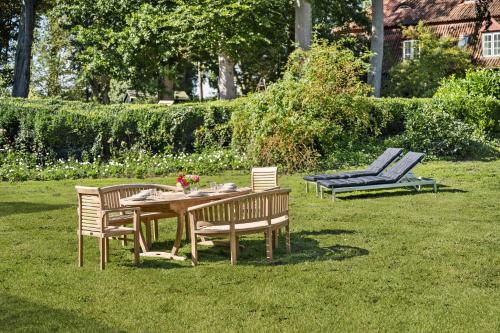 a table and chairs and a bench in a yard at GUT KLETKAMP "Storchennest" - Ferienwohnung im Schlossturm mit 3 Schlafzimmern I Panorama-Turmzimmer mit Naturblick I Gemeinschaftsgarten I 15 Min zur Ostsee I Küche I Parkplatz I WLAN in Kletkamp