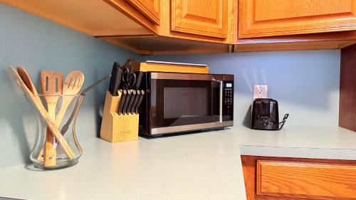 a microwave on a kitchen counter with utensils at The Wavestay I 4 min walk to Beach in Satellite Beach