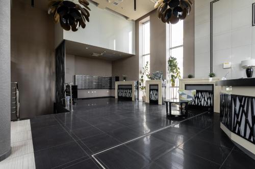 a large lobby with a black tile floor and windows at ALE Jerozolimskie Varsovia Apartments in Warsaw