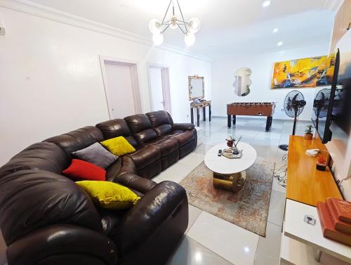 a living room with a leather couch and a table at AB Luxury 2 bedroom Apartment with 24hr Electricity, Wifi, Fully Equipped Kitchen in Lagos
