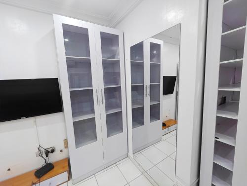 a white closet with glass doors and a tv at AB Luxury 2 bedroom Apartment with 24hr Electricity, Wifi, Fully Equipped Kitchen in Lagos