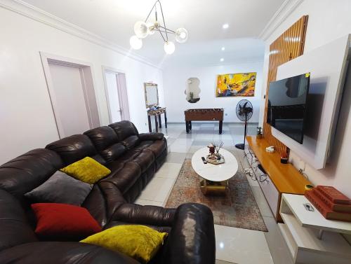 a living room with a leather couch and a tv at AB Luxury 2 bedroom Apartment with 24hr Electricity, Wifi, Fully Equipped Kitchen in Lagos