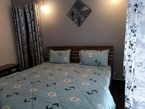 a bedroom with a bed with a blue comforter at Gaani Homestay Uttarkashi in Uttarkāshi