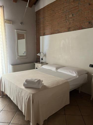 a bedroom with a white bed with a brick wall at Hotel Villa Costanza in Pontenure