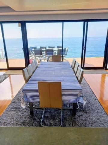 a dining room with a table and chairs and the ocean at Ocean Front - Port Kembla in Port Kembla