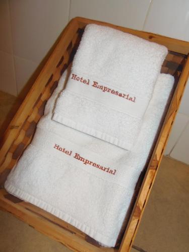 ロス・アンヘレスにあるHotel Empresarialの木の盆に積み重ねたタオル