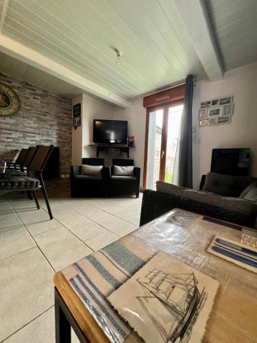 a living room with couches and a tv and a table at Les marins des LYS, Cayeux sur mer, Baie de somme in Cayeux-sur-Mer