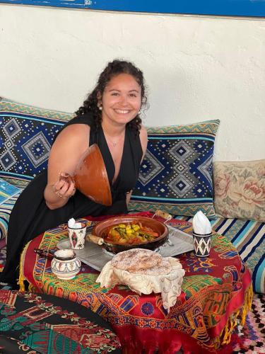 a woman sitting at a table with a plate of food at Hostel blue house Taghazout in Taghazout
