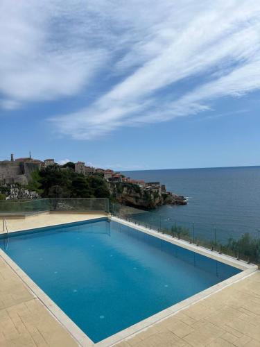 a large blue swimming pool next to the ocean at Ornament Liman - Infinity Pool with Old Town View Apartments in Ulcinj