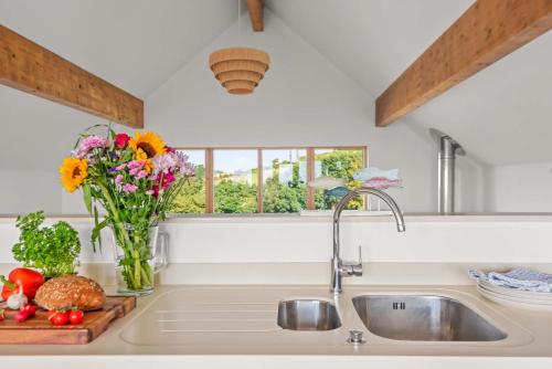 a kitchen sink with a vase of flowers and a window at House 27 in Looe