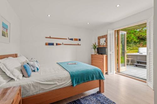 a bedroom with a bed and a balcony with a tub at House 27 in Looe