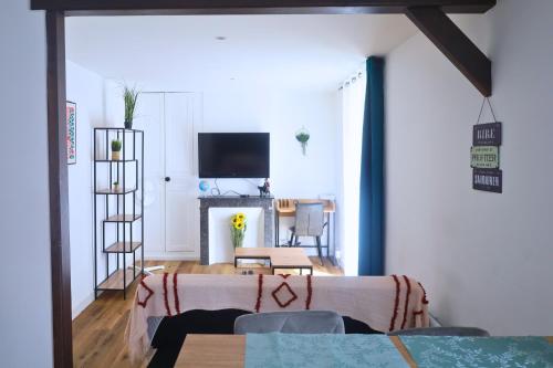 a living room with a table and a tv at Le Halo Secret, 40min de Disney, 5 min du centre Coulommiers in Coulommiers