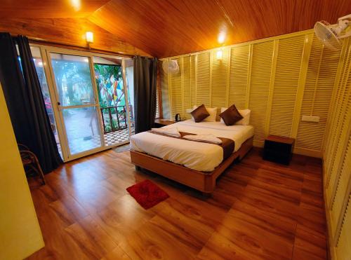 a bedroom with a bed and a large window at Darsy Residency and beach cottages in Agonda