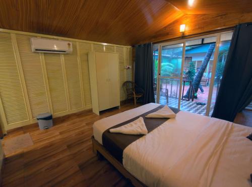 a bedroom with a bed and a sliding glass door at Darsy Residency and beach cottages in Agonda