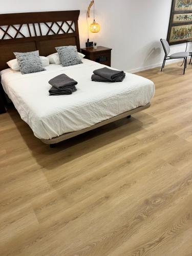 a bedroom with a bed with white sheets and wooden floors at Apartamento Castillejos 4 in Tarifa