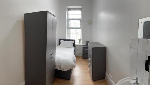 a bedroom with a bed and a cabinet and a window at Wicker guesthouse in Sheffield