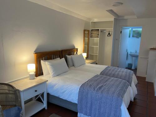 a bedroom with a bed and a table with a night stand at Langebaan Stay Guest House in Langebaan