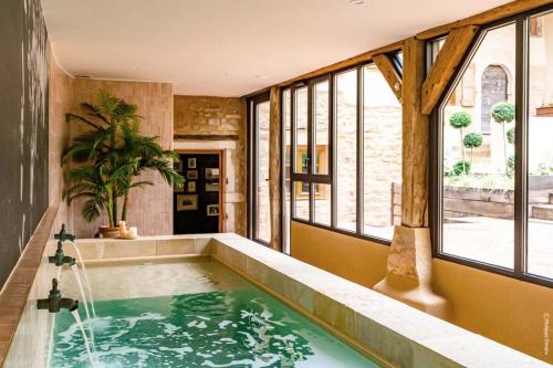 a pool in a room with windows and a tub at Country Villa With Indoor Pool In Beaujolais in Romanèche-Thorins