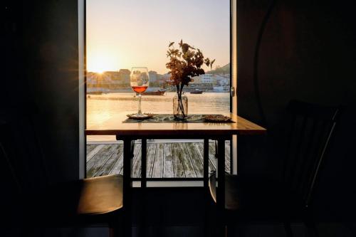 a table with two glasses of wine and a window at Alma Flotante Muxía in Muxia