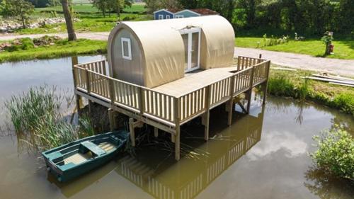 a house on a dock with a boat in the water at Camping Le Romantic in Steenvoorde