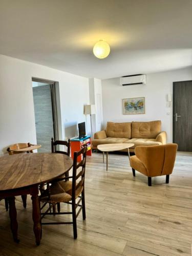 un salon avec une table, des chaises et un canapé dans l'établissement Appartement centre ville, à Propriano