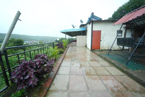 a walkway next to a building with a fence at Berry Hills in Mahabaleshwar