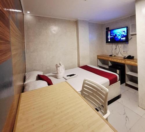 a hotel room with two beds and a television at El Grande Inn Piy Margal Sampaloc Manila in Manila