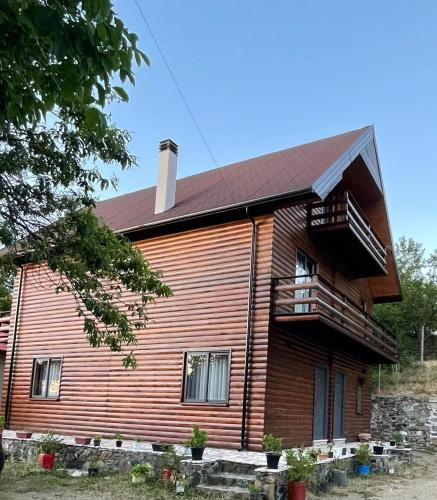 a large wooden house with a porch and a balcony at Mirjana Guesthouse in Pukë