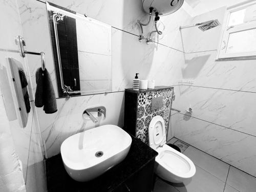a white bathroom with a sink and a toilet at Rishikesh-Tapovan - Lakshman Jhula - Triveni Ghat in Narendranagar