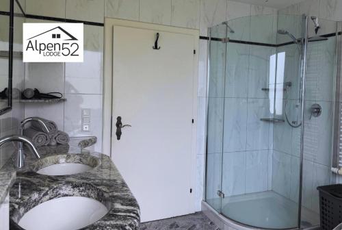 baño con ducha, 2 lavabos y puerta de cristal en Ferienwohnung Alpenlodge 52, en Aschau